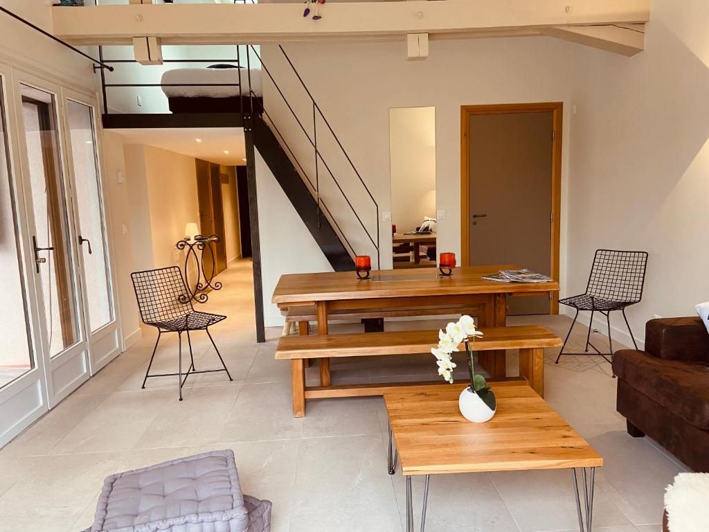 Le séjour d’un appartement, avec sa table de bois, son canapé et l’escalier métallique qui monte à la mezzanine