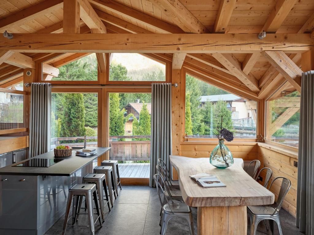 La cuisine du chalet, son îlot de pierre, ses tabourets hauts et sa verrière au fond