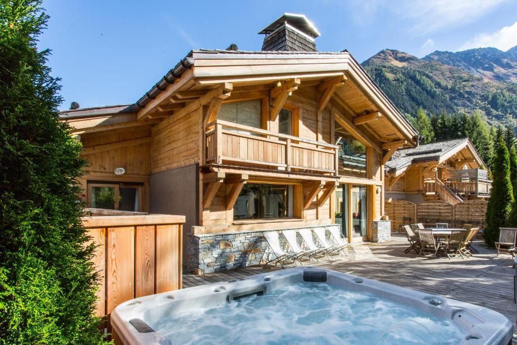 Le jacuzzi encastré dans la terrasse de bois, fumant, avec la neige et les sapins autour
