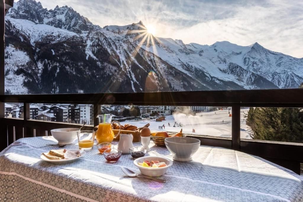 Une table de petit-déjeuner dressée sur le balcon, face aux sommets enneigés éclairés par le soleil levant
