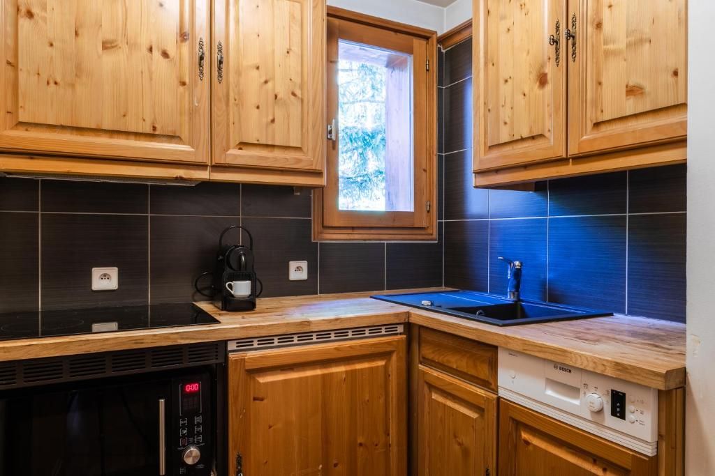La kitchenette d’une suite, en bois clair, avec ses plaques, son micro-ondes et son lave-vaisselle