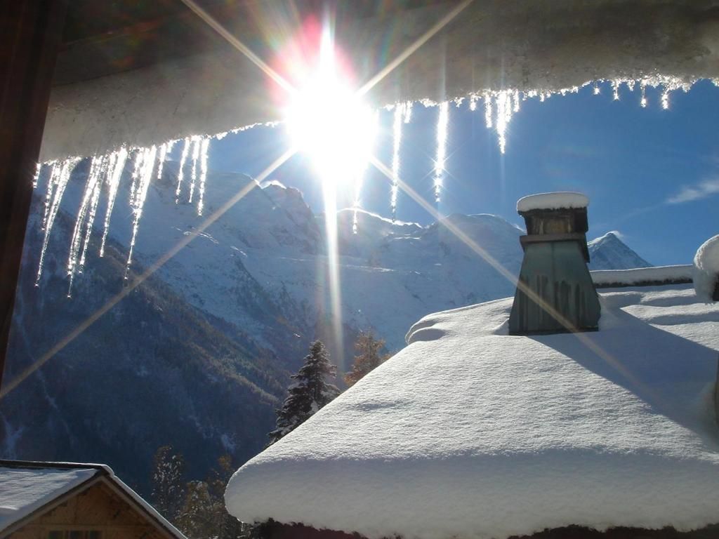 Le toit enneigé et ses stalactites, à contre-jour, au-dessus du versant d’en face
